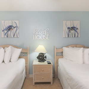 Rest in this guest bedroom with double beds, beach decor, and a charming lamp with soft lighting