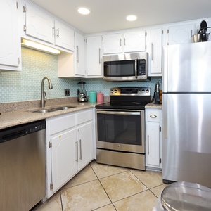 This kitchen features sleek stainless appliances, stylish tile backsplash, and ample counter space for meal preparation