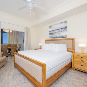 Master bedroom featuring a plush king bed, cozy twin sleeping chair, and a glimpse of a dining area through the curtains