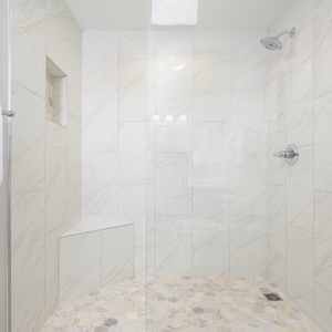 Experience a luxurious walk-in shower in this guest bathroom with elegant marble tiles and a stylish hexagonal floor