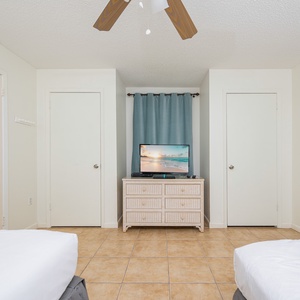Unwind in this inviting bedroom with two beds, a TV, and easy access to the adjoining bathroom