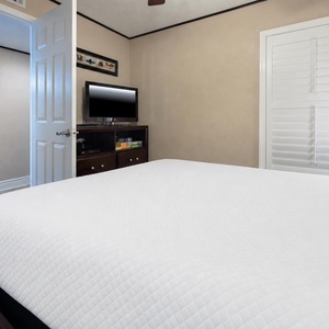 This cozy guest bedroom features a comfortable bed, a flat-screen TV, and a welcoming atmosphere with soft, neutral tones