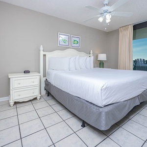 Master suite bedroom featuring a king bed, a nightstand, and access to the extended balcony with a view of the beach