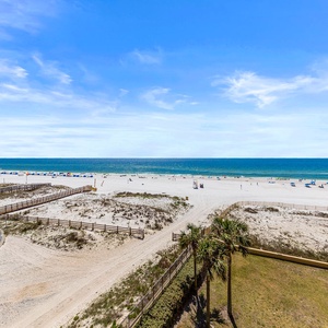 Expansive view of the beach with white sand, colorful umbrellas, and a serene blue sea under a clear sky