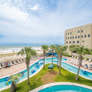 Vibrant pool area of the lazy river from the balcony, surrounded by palm trees creates a perfect tropical escape