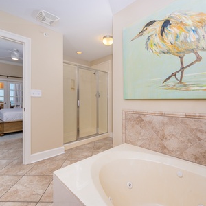 The master bath features a relaxing jetted tub, a glass walk-in shower, and a serene view of the beach through the master