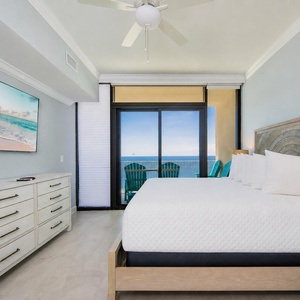 Serene master bedroom featuring a king bed, a large TV, and beachfront balcony access