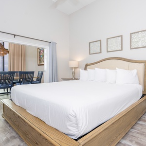 Elegant master bedroom featuring a comfortable king bed looking into the charming dining area with a coastal view