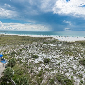 Gulf views stretch across the horizon, with a pool area below and beach access just beyond the lush green dunes