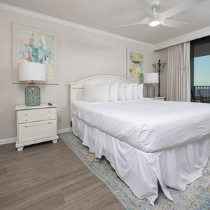 Soothing master bedroom features a plush king bed, coastal artwork, and access to the balcony with a view of the beach