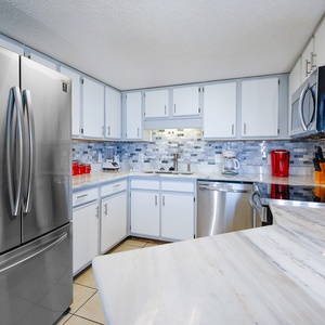 The modern kitchen features sleek cabinetry, a marbled countertop, and a stylish backsplash, perfect for culinary adventures