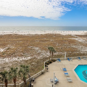 Vibrant pool area with lounge chairs overlooks the expansive beach and gulf waters, creating a perfect spot for relaxation
