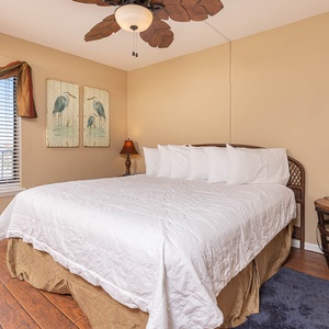This guest bedroom features a large bed, decorative bird artwork, and a window with a lovely view