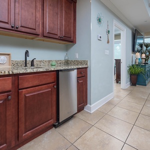 Enjoy preparing drinks at the stylish wet bar, featuring rich wood cabinetry, a sleek countertop, and ice maker