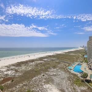 Stunning view of the beach and inviting turquoise waters, and a pool area adjacent to the shoreline