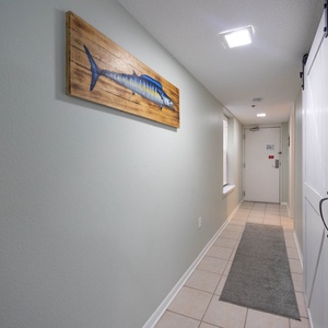 A welcoming hallway features a decorative fish artwork, tile flooring, and natural light from a window
