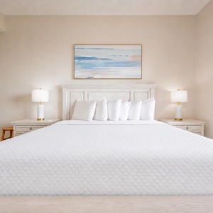 A king master suite awaits your rest with gentle lamps glowing and a view stretching toward the coast beyond