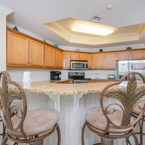 Bright kitchen featuring granite countertops, stainless appliances, and elegant bar seating for a welcoming dining experience