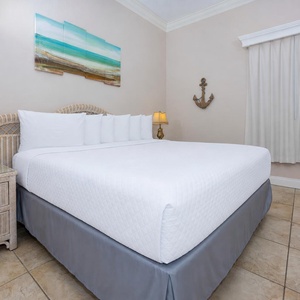 Experience restful nights in the inviting bedroom featuring a king bed, coastal decor, and a TV
