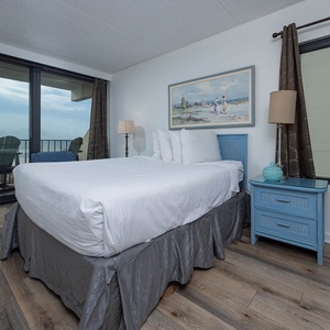 The master bedroom features a comfortable bed and stunning beachfront views from the large windows