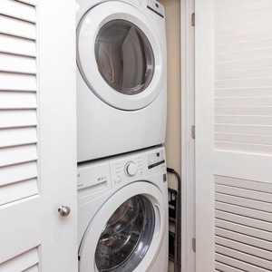 This laundry area features a stacked washer and dryer behind a stylish louvered door for your convenience