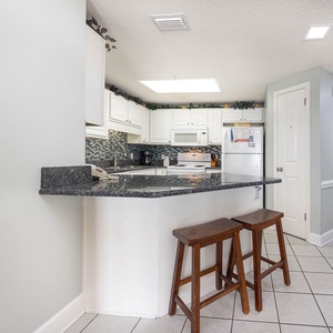 Enjoy casual meals at the breakfast bar, featuring sleek countertops and a view into the bright kitchen space