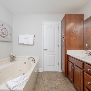 Relax in this master bath featuring a jetted tub, walk-in shower, stylish cabinetry, and beautiful shell-themed decor
