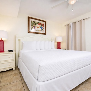 The bedroom features a plush king bed, vibrant red lamps, and tasteful artwork, creating a relaxing atmosphere