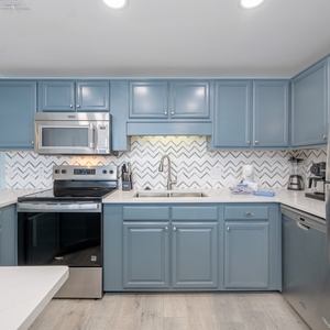 Soft light shines on the kitchen's blue cabinets as the Keurig ready for your morning brew awaits you