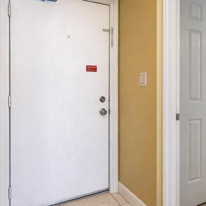 This inviting entryway leads to a cozy guest bedroom featuring a comfortable bed and charming nautical decor