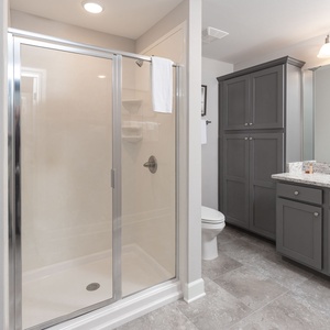 Enjoy a relaxing shower after a day at the beach in this guest bath with stylish cabinetry and spacious vanity