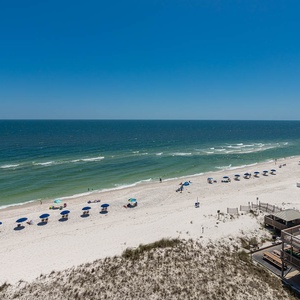 This stunning beachfront view showcases vibrant blue umbrellas lining the sandy shore, perfect for a relaxing getaway
