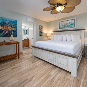 Relax in this inviting master bedroom featuring a plush king bed, coastal decor, and a vibrant fish painting