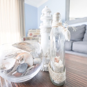 Decorative coastal accents, including a lighthouse and seashells, enhance the inviting ambiance of the living area