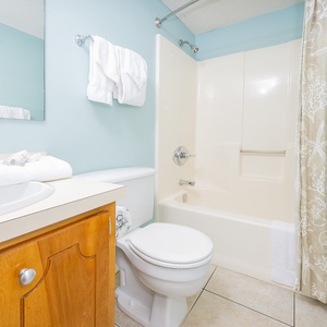The bathroom features a clean design with a spacious vanity, fresh towels, and a relaxing tub for your comfort