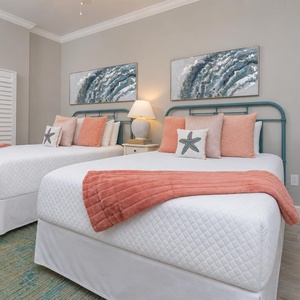 Unwind on plush queen beds beneath teal headboards as the bedside lamp casts warm light in this charming guest suite