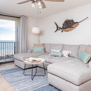 Living area features a large sectional sofa with colorful pillows, a stylish coffee table, and expansive gulf views