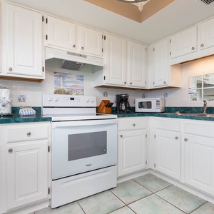 Inviting kitchen featuring white cabinetry and appliances, a vibrant turquoise countertop, and coffee maker
