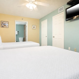 Relax in this guest bedroom featuring two queen beds, a TV, and soft colors that create a welcoming atmosphere