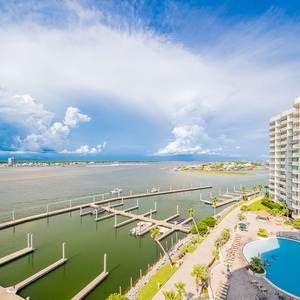 Breathtaking waterfront view showcasing docks, lush landscaping, and a sparkling pool under a bright blue sky