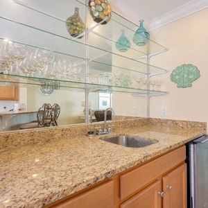 Wet bar area with granite countertops and glassware create an inviting atmosphere in this modern kitchen with a scenic view