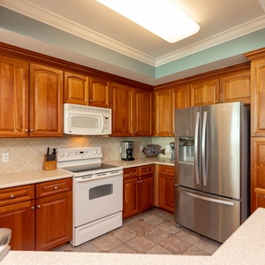 Prepare meals in this spacious kitchen featuring rich wood cabinetry, white and stainless appliances, and ample counter space