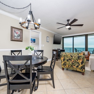 This inviting dining area features a round table, stylish black chairs, and a view of the beachfront through large windows
