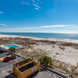 This bright view showcases a beach front with soft white sands and a sparkling pool, perfect for relaxing vacations