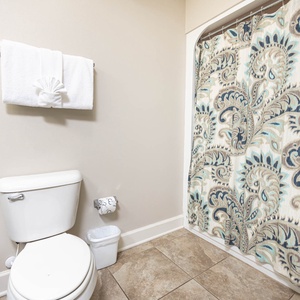 This bathroom features elegant patterned shower curtains, fresh towels, and a clean, modern design for a refreshing retreat