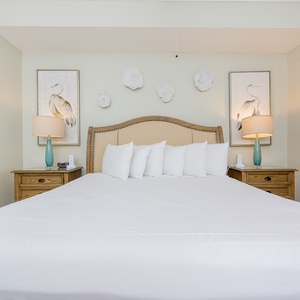 Relax in this inviting master bedroom featuring a king-size bed, elegant decor, and soothing coastal artwork