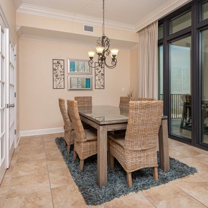 This dining area features a stylish table with woven chairs and large windows offering a serene view of the state park