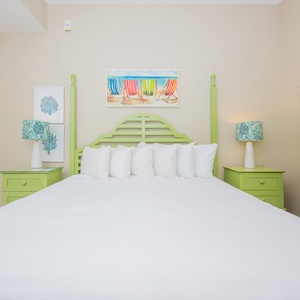 Green furnishings complement a spacious king bed adorned with fluffy white pillows, creating a cheerful and inviting vibe