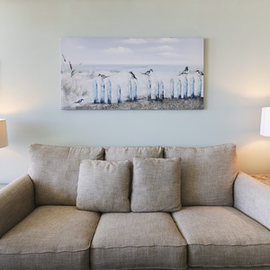 The living area features a comfortable couch, soft lighting, and beach-themed artwork, perfect for relaxation