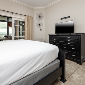 The master bedroom features a king, a TV for entertainment, stylish decor, and French doors that open to the dining area
